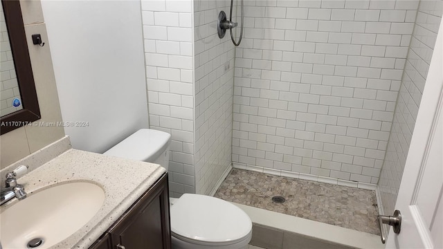 bathroom with vanity, toilet, and tiled shower