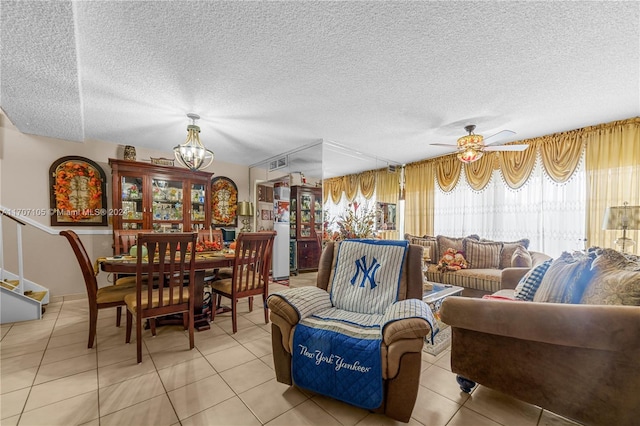 dining room featuring ceiling fan with notable chandelier, light tile patterned floors, and a textured ceiling