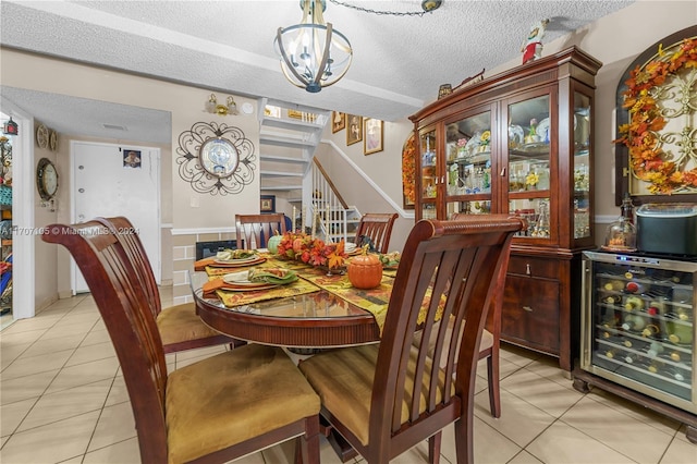 tiled dining space with a textured ceiling, wine cooler, and a chandelier