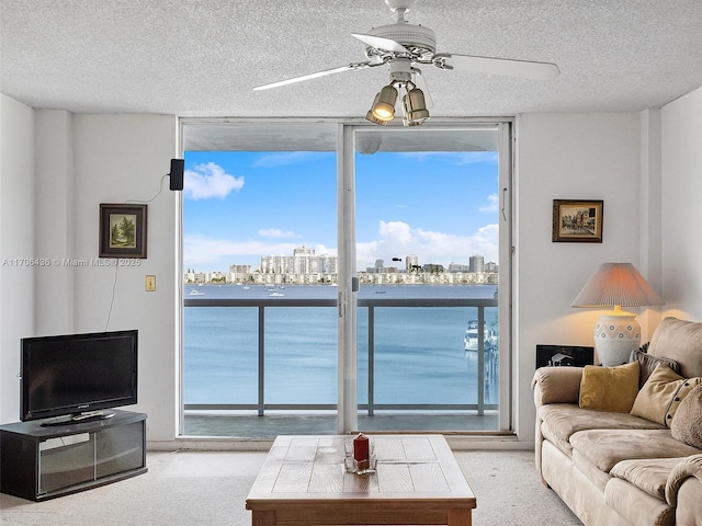 living room featuring ceiling fan, expansive windows, and light carpet