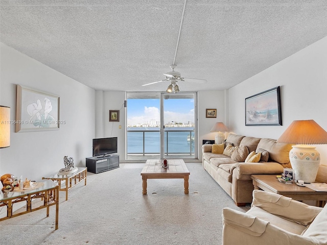 carpeted living room with a textured ceiling, a wall of windows, and ceiling fan