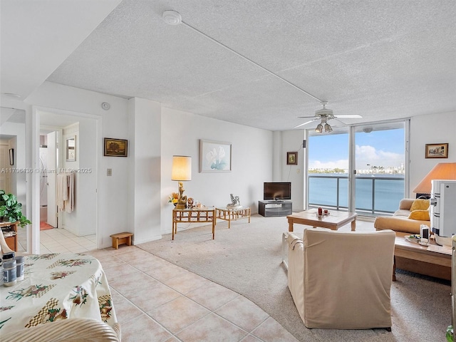 carpeted living room featuring ceiling fan, expansive windows, and a textured ceiling