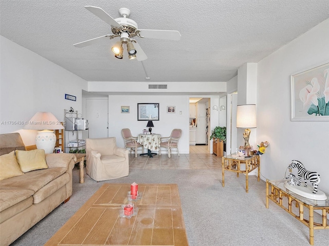 carpeted living room featuring ceiling fan and a textured ceiling