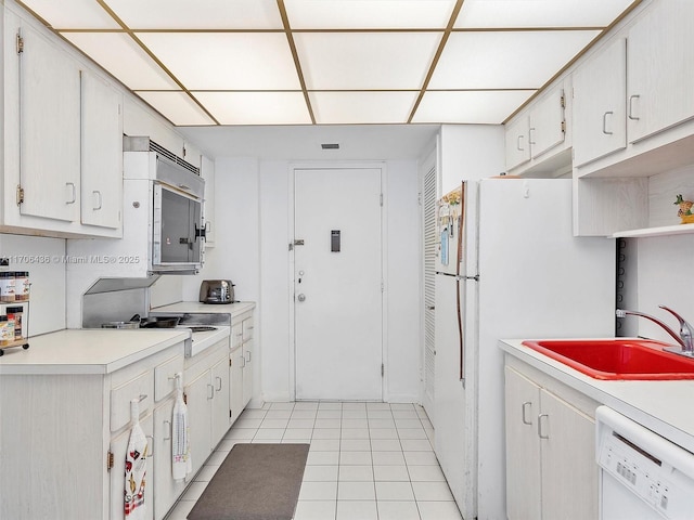 kitchen featuring sink, white cabinets, light tile patterned flooring, and white appliances