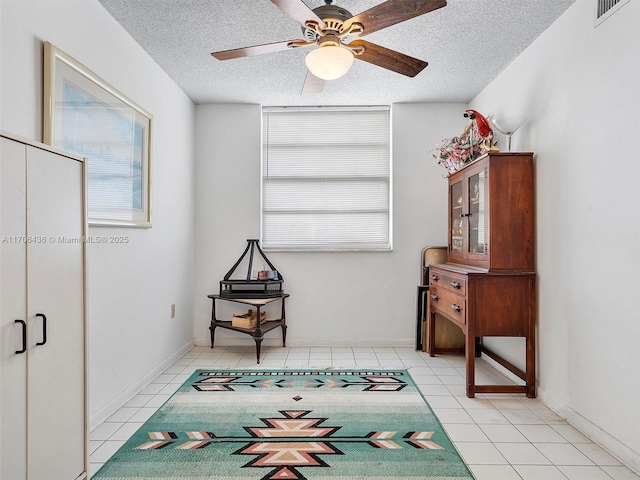 living area with ceiling fan, light tile patterned floors, and a textured ceiling