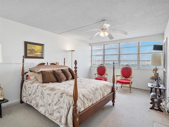 carpeted bedroom featuring ceiling fan and a textured ceiling