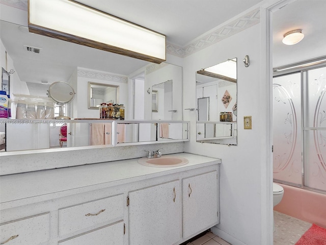 full bathroom with tile patterned floors, vanity, toilet, and bath / shower combo with glass door