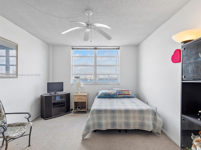 bedroom with ceiling fan, light carpet, and a textured ceiling