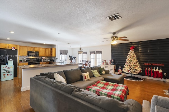 living room with ceiling fan, a textured ceiling, and light hardwood / wood-style flooring