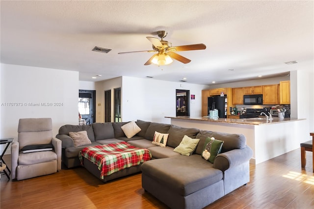 living room featuring ceiling fan, hardwood / wood-style floors, and a textured ceiling