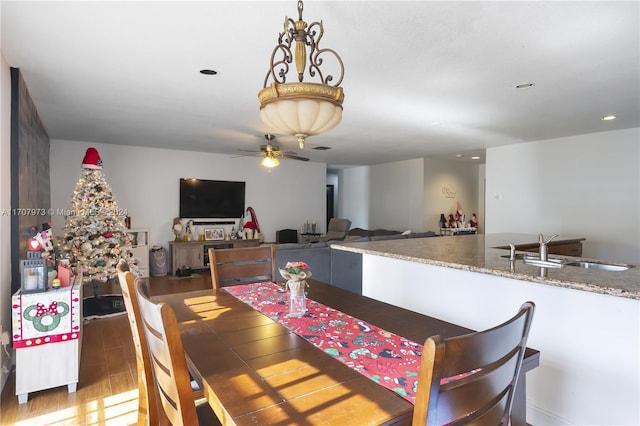 dining area featuring ceiling fan, sink, and wood-type flooring