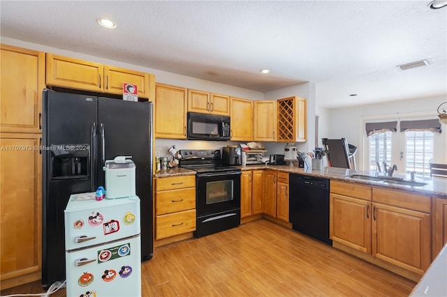 kitchen featuring black appliances, light stone counters, sink, and light hardwood / wood-style flooring