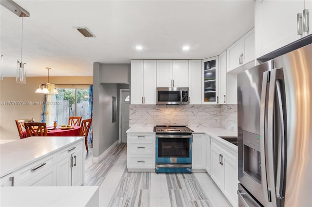 kitchen featuring stainless steel appliances, white cabinetry, and hanging light fixtures