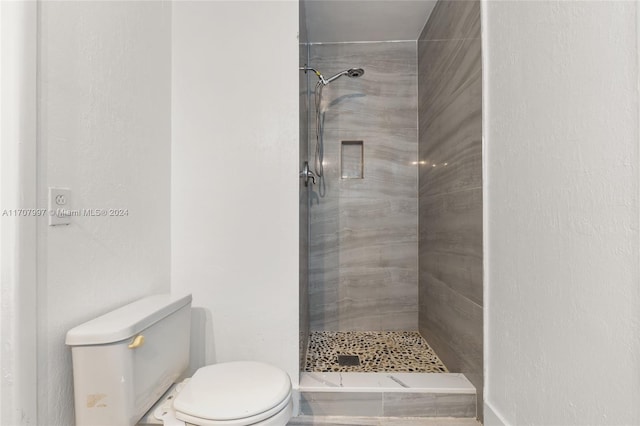 bathroom with a tile shower and toilet