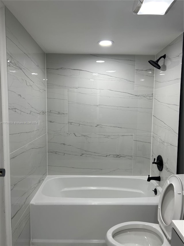 full bathroom featuring vanity, tiled shower / bath combo, and toilet