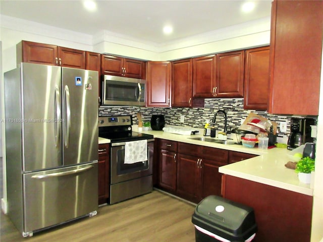 kitchen featuring backsplash, crown molding, sink, light hardwood / wood-style flooring, and stainless steel appliances