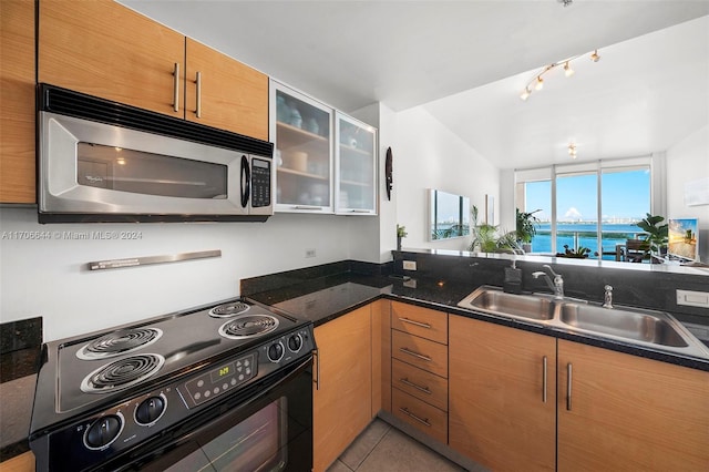 kitchen featuring light tile patterned flooring, electric range, dark stone counters, and sink