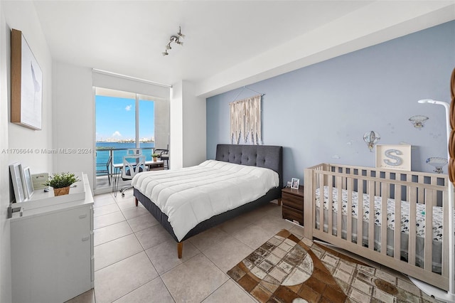 tiled bedroom featuring rail lighting and a water view