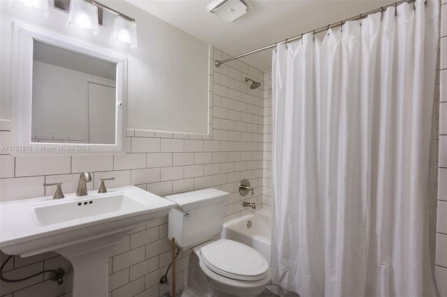 bathroom with shower / bath combo, toilet, and tile walls