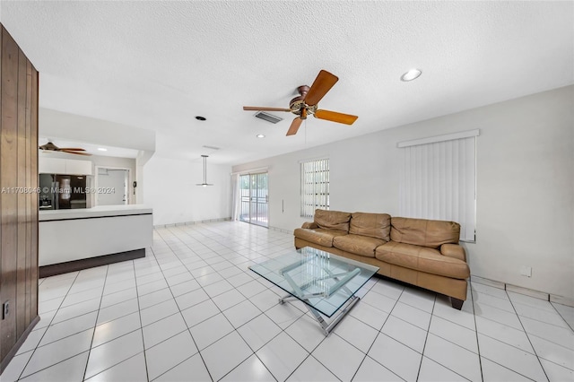 tiled living room with ceiling fan and a textured ceiling