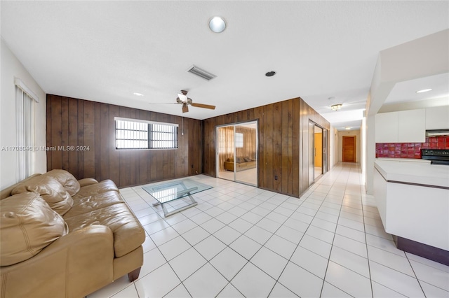 tiled living room featuring wooden walls and ceiling fan