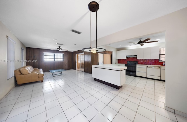 kitchen featuring black electric range, white dishwasher, pendant lighting, white cabinets, and wood walls