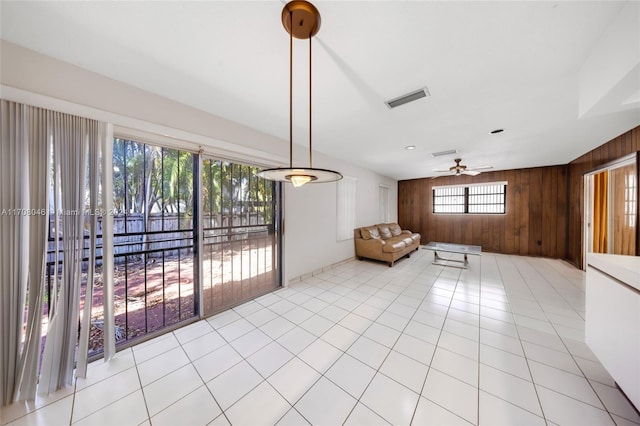 interior space featuring ceiling fan, light tile patterned floors, and wooden walls