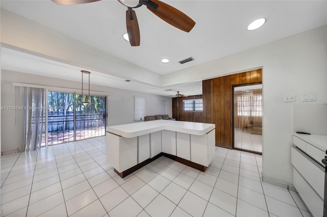 kitchen featuring white cabinetry, ceiling fan, hanging light fixtures, and wood walls