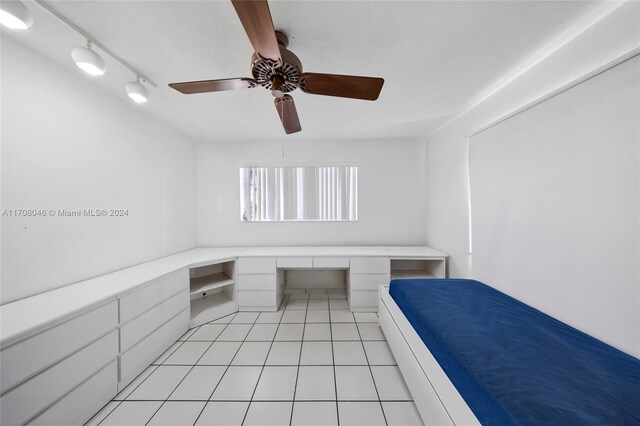 unfurnished bedroom with ceiling fan, light tile patterned floors, and rail lighting