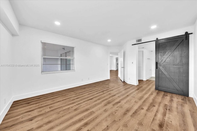 1200 SW 130th Ave Unit 412G, Pembroke Pines, FL 33027 - unfurnished bedroom with a barn door, baseboards, wood finished floors, and recessed lighting