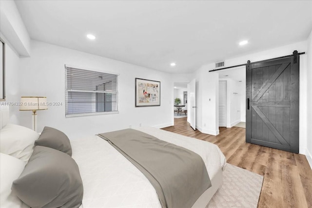 bedroom with wood-type flooring and a barn door