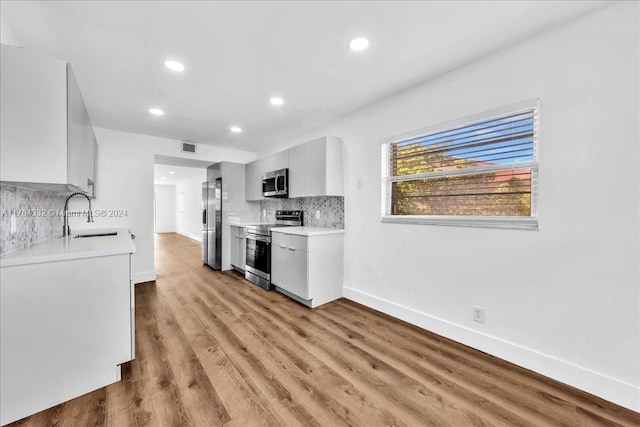 kitchen featuring white cabinetry, sink, light wood-type flooring, and appliances with stainless steel finishes