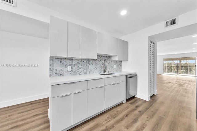 kitchen featuring tasteful backsplash, dishwasher, light wood-type flooring, and sink