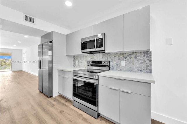 kitchen featuring gray cabinetry, decorative backsplash, stainless steel appliances, and light hardwood / wood-style floors