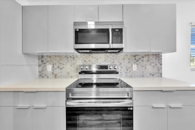 kitchen featuring tasteful backsplash, white cabinets, and appliances with stainless steel finishes