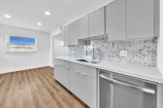 kitchen with dishwasher, light hardwood / wood-style floors, tasteful backsplash, and sink