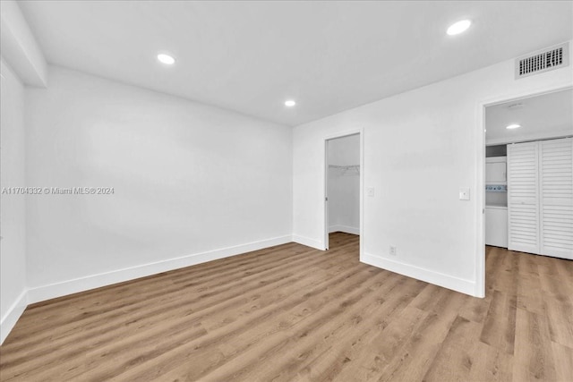 unfurnished bedroom featuring a walk in closet, a closet, and light hardwood / wood-style floors