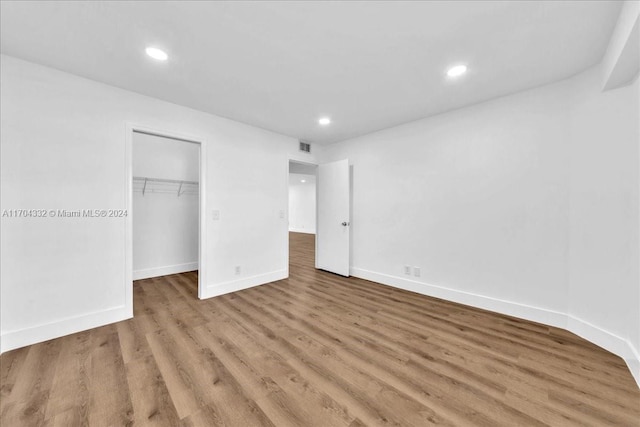 unfurnished bedroom featuring wood-type flooring, a walk in closet, and a closet