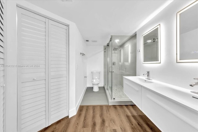 bathroom featuring hardwood / wood-style flooring, vanity, toilet, and a shower with shower door