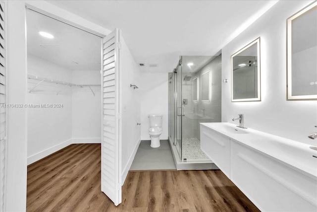 bathroom with an enclosed shower, vanity, toilet, and wood-type flooring