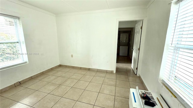 unfurnished room with plenty of natural light, light tile patterned flooring, and crown molding