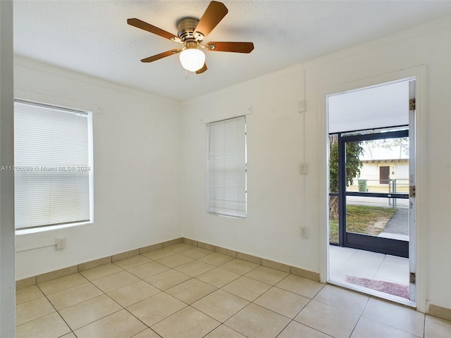 tiled empty room featuring ceiling fan and crown molding