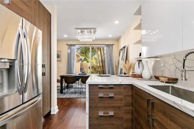 kitchen featuring decorative backsplash, stainless steel refrigerator with ice dispenser, dark hardwood / wood-style flooring, sink, and an inviting chandelier