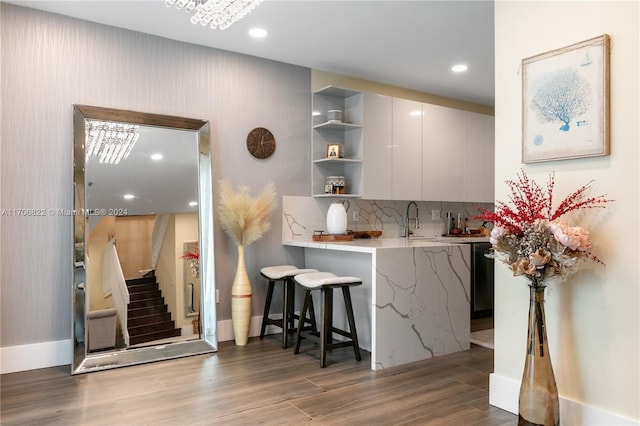 kitchen featuring a breakfast bar, dark hardwood / wood-style floors, decorative backsplash, black dishwasher, and kitchen peninsula