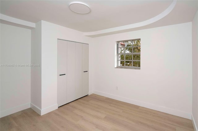 unfurnished bedroom with light hardwood / wood-style flooring and a closet