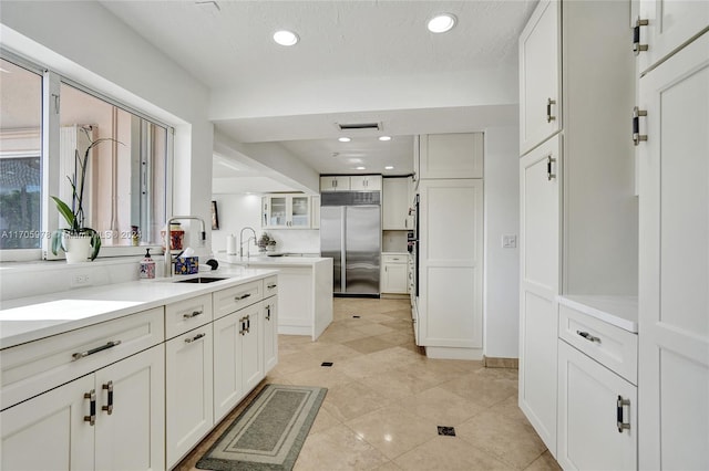 kitchen featuring white cabinetry, stainless steel built in refrigerator, and sink