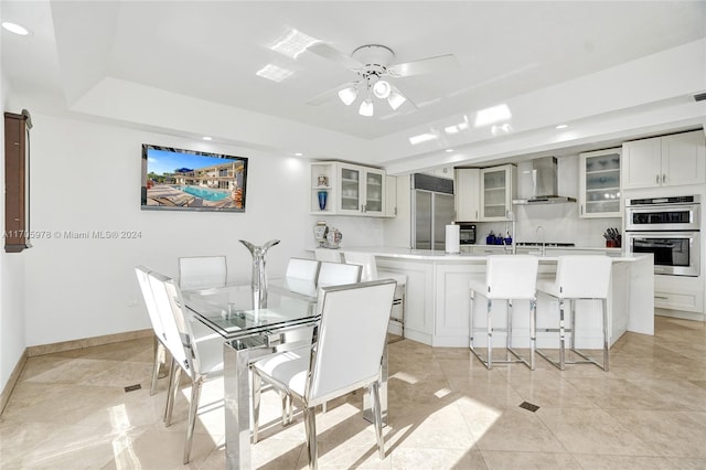 dining room with a tray ceiling, ceiling fan, and sink