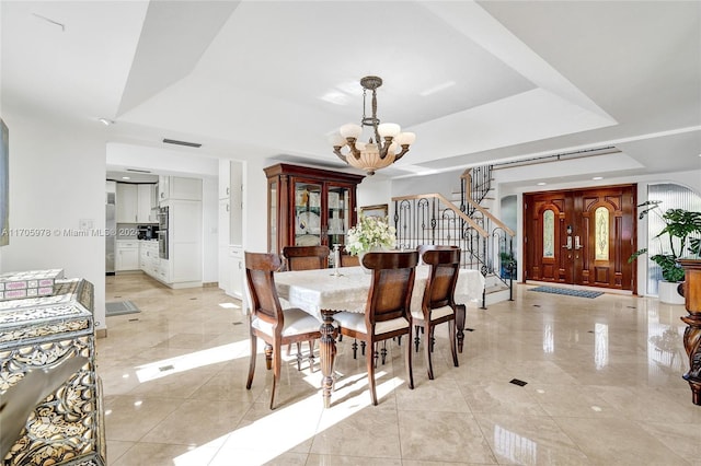 dining space with a tray ceiling, light tile patterned floors, and a notable chandelier