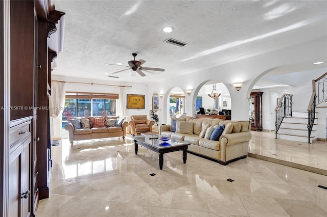 living room featuring ceiling fan with notable chandelier, a textured ceiling, and a wealth of natural light