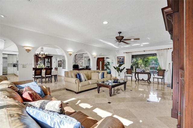 living room with ceiling fan with notable chandelier and ornamental molding